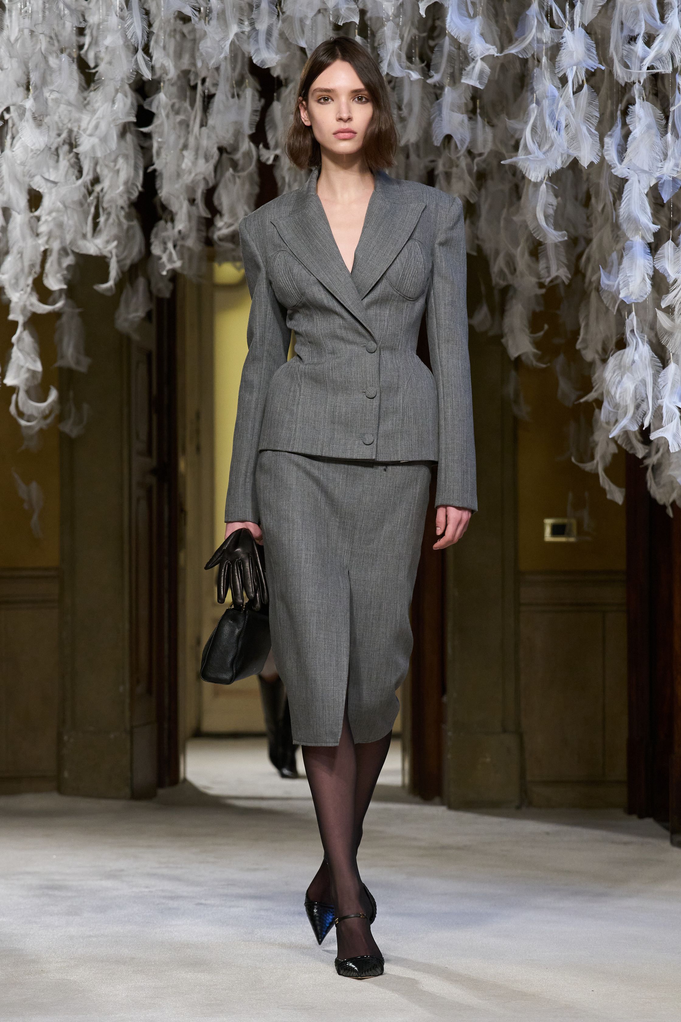 Elisabetta Franchi在灰调西装与黑色紧身礼服之间释放强烈女性魅力，紧束腰线与高开衩设计强化性感比例，结构西装与透视蕾丝交织出自信、华丽且极具舞台感的意式表达-顽石频道趋势研究